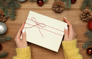 Woman with Christmas gift at wooden table, top view