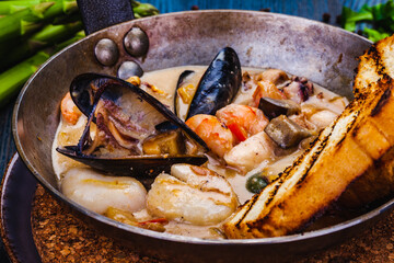 Mixed seafood saute served with toasted bread in a pan