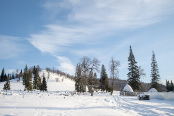 Winter village in the mountains. Trees and fences are covered with snow and frost.