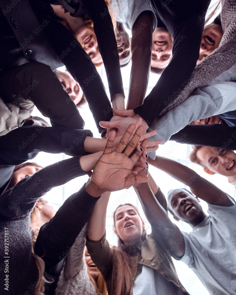 Sticker bottom view. group of happy young people making a stack of hands