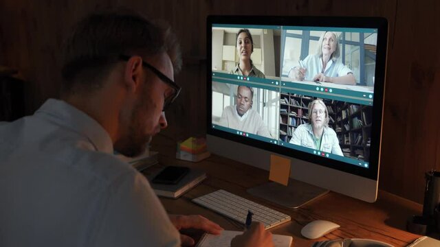 Young business man talking with diverse colleagues in virtual video conference group chat using computer at home office. Online professional videoconference communication, social distance work concept