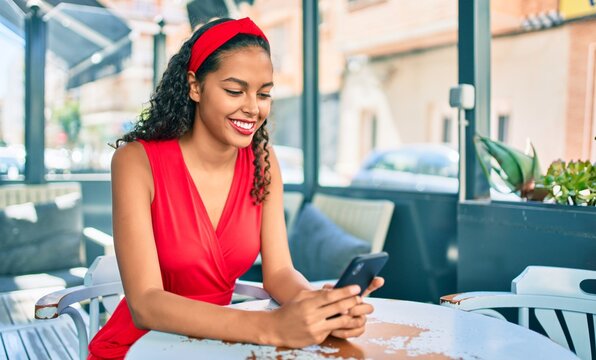 Young african american girl smiling happy using smartphone sitting on the table at coffee shop terrace.