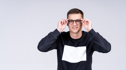 Naklejka premium Handsome man presenting modern glasses on light gray background. Casual sweater with copy space.