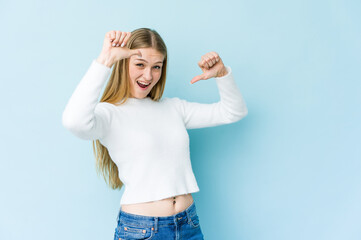 Young blonde woman isolated on blue background feels proud and self confident, example to follow.