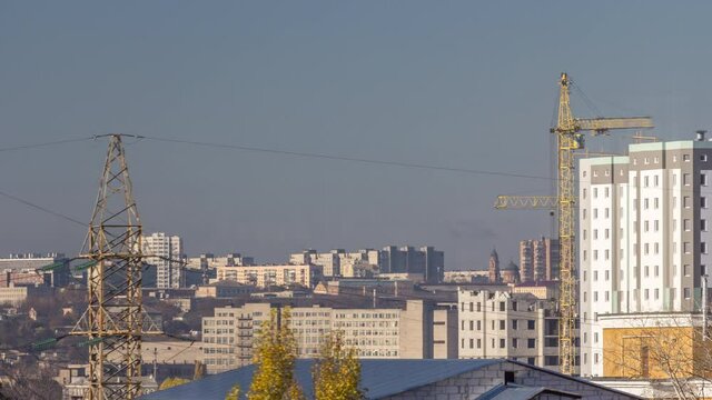 Crane and building construction site in a big city aerial timelapse during all day. Workers laying briks walls of new residential appartment house near high voltage power lines tower