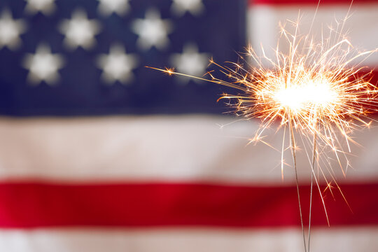 Bright burning sparklers against American flag, closeup. Space for text