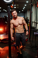 Strong athletic man fitness model. Guy with nacked torso showing six pack abs. Modern gym on the...