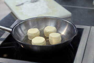 cooking cottage cheese pancakes in a skillet in the kitchen