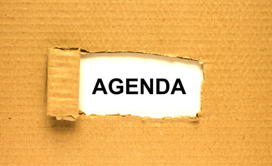 The word Agenda appearing behind torn brown paper