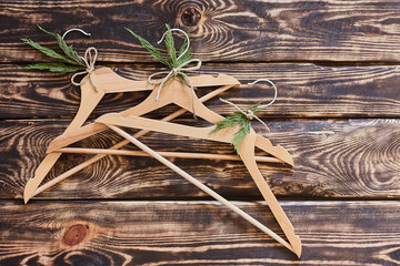 Wooden hangers with sprig of cypress on dark wooden background. Eco-friendly, Chic, Cozy, Sustainable Sale concept. Zero waste Black friday. Space for text.