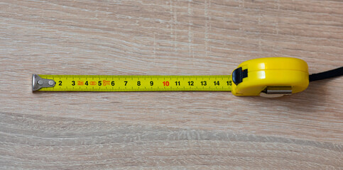 Tape measure on the table. Fifteen inches on a tape measure. The entire tape is in focus.