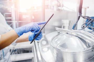 Dairy factory production, engineer operator check quality with computer tablet in milk tank