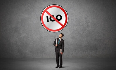 Young business person holdig traffic sign with ICO abbreviation, technology solution concept