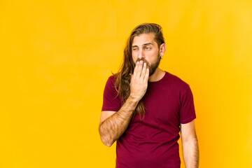 Young man with long hair look yawning showing a tired gesture covering mouth with hand.