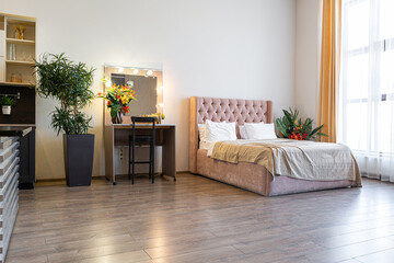 Contemporary ordinary design of spacious studio in soft warm colors. Simple furniture. Light large room with sunlight. Daytime. Tiled brown floor and white walls .