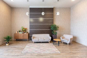 Contemporary ordinary design of spacious studio in soft warm colors. Simple furniture. Light large room with sunlight. Daytime. Tiled brown floor and white walls .