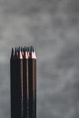 Simple graphite pencils on grey background. Black pencils, space for text