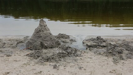 The remains of a sand castle on the shores of a lake

