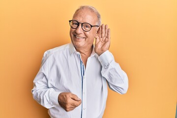 Senior caucasian man wearing casual clothes and glasses smiling with hand over ear listening and...
