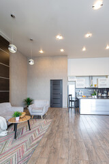 Contemporary ordinary design of spacious studio in soft warm colors. Simple furniture. Light large room with sunlight. Daytime. Tiled brown floor and white walls .