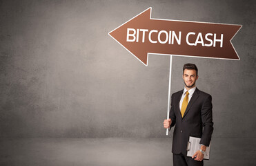 Young business person in casual holding road sign with BITCOIN CASH inscription, business direction concept