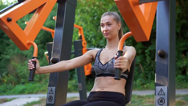 Sportive female training exercise machine outdoor gym summer park Middle age caucasian woman dressed sportswear workout outside on simulator sport ground. Healthy lifestyle concept, High quality 4k 