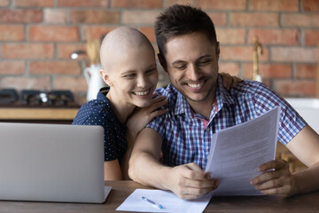 Good news. Happy excited young couple husband and wife diagnosed with oncology receiving test results with positive dynamic, reading letter from leading cancer center ready to admit her for treatment