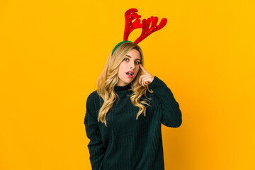 Young blonde caucasian woman wearing reindeer horns showing a disappointment gesture with...