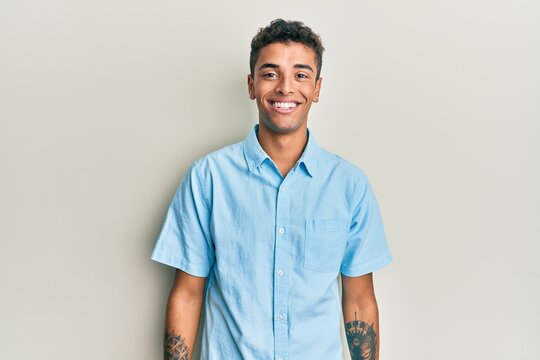Young handsome african american man wearing casual clothes looking positive and happy standing and smiling with a confident smile showing teeth