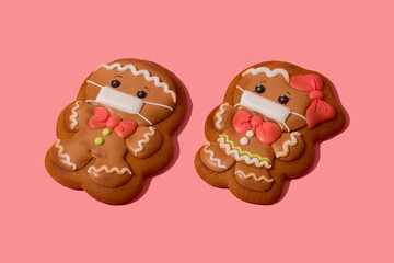 Christmas gingerbread man and woman in medicine mask on the rose background. Be responsible. Couple of gingerbread