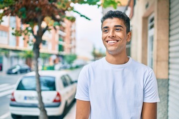 Young latin man smiling happy walking at the city.