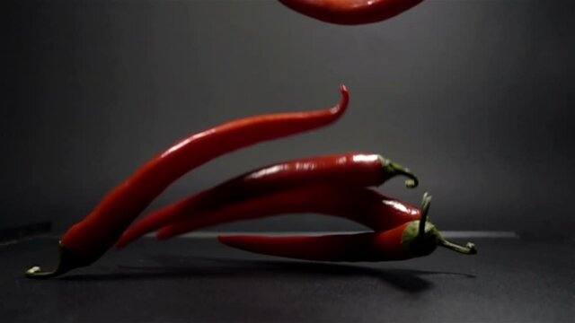 Red Chili Peppers falling in slow motion on black background