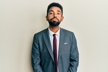 Handsome young hispanic man wearing business suit and tie showing and pointing up with fingers number ten while smiling confident and happy.