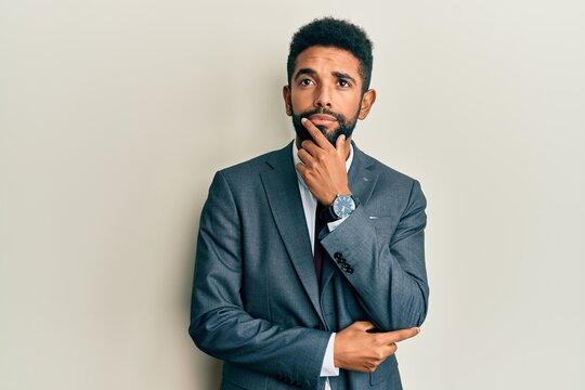 Handsome young hispanic man wearing business suit and tie surprised pointing with finger to the side, open mouth amazed expression.
