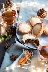 mince pies on a plate served with black tea. A mince pie is a traditional Christmas sweet pie, filled with a mixture of dried fruits and spices.