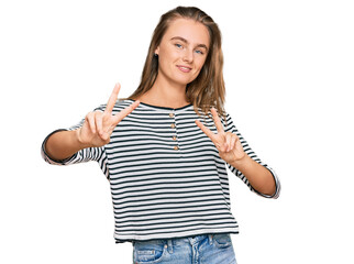 Obraz na płótnie Canvas Beautiful blonde woman wearing casual clothes smiling looking to the camera showing fingers doing victory sign. number two.