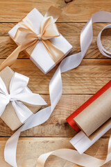 Packed boxes with gifts and paper and ribbons for packaging on a wooden background. Gift wrapping concept. Gifts for the holiday. Christmas gifts. New Year's greetings. Birthday gifts.