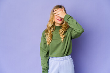 Young caucasian blonde woman covers eyes with hands, smiles broadly waiting for a surprise.