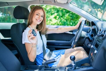 Young beautiful blonde woman smiling happy sitting at the car showing key