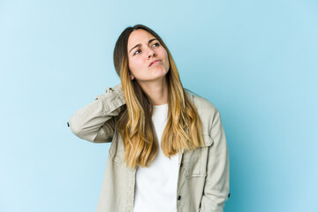Fototapeta premium Young caucasian woman isolated on blue background having a neck pain due to stress, massaging and touching it with hand.