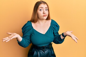 Young beautiful redhead woman wearing elegant and sexy look clueless and confused expression with...