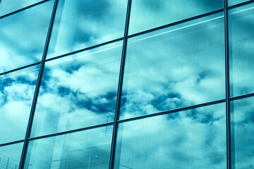 Modern glass facade of an office building, reflection of the sky in the Windows.