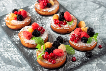 Fresh small homemade fruit tarts with raspberries, currants and blackberries