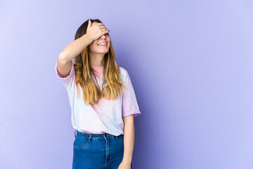 Young caucasian woman isolated on purple background laughs joyfully keeping hands on head. Happiness concept.