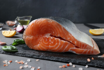 Fresh raw salmon with ingredients on slate board on dark background. Closeup. Horizontal format