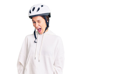Beautiful brunette young woman wearing bike helmet and sporty clothes winking looking at the camera with sexy expression, cheerful and happy face.