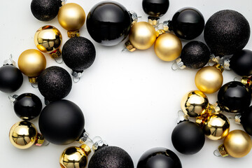 Surprise gift. Golden New Year balls, black baubles in xmas composition on white background for greeting card. Winter festive composition with copy space.