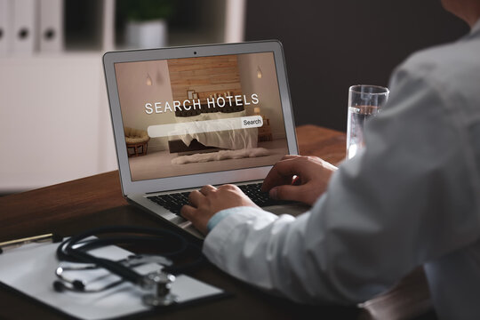 Doctor Searching Hotel Using Laptop At Table, Closeup. Booking Online Service