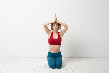 A woman in blue jeans practices yoga on a light background indoors and a slim figure in gymnastics