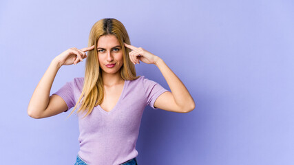 Young blonde caucasian woman focused on a task, keeping forefingers pointing head.